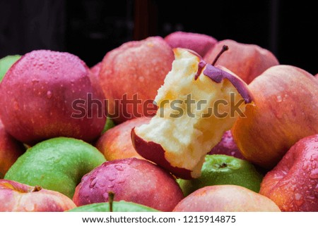 Apple core leftover among heap of fresh red and green apples mix closeup side view Royalty-Free Stock Photo #1215914875