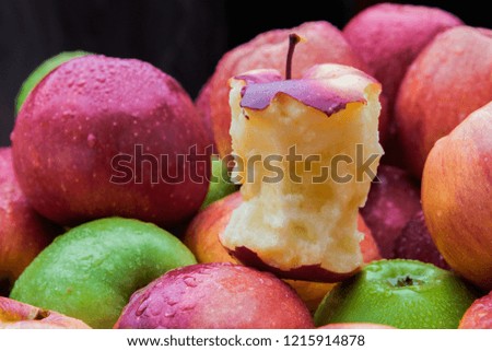 Apple core leftover among heap of fresh red and green apples mix closeup side view Royalty-Free Stock Photo #1215914878