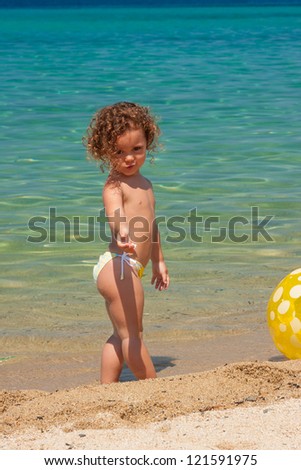 cute little girl playing with a ball on the beach