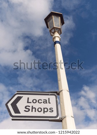 English Street Sign for Local Shops against blue sky with clouds background.
