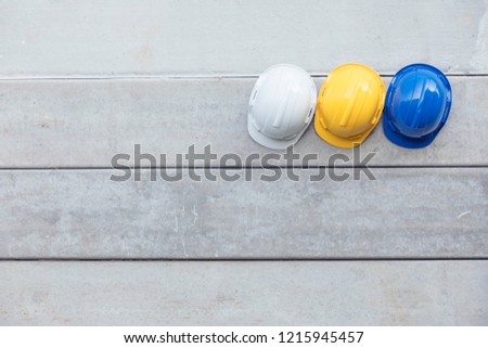 Safety helmet Blue, Yellow, White On the concrete wall,Hats for engineering and construction hang on the cement wall.safety helmet  On the concrete  Royalty-Free Stock Photo #1215945457