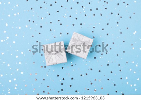 Christmas gift with blue ribbon on blue pastel background with festive decorations. Christmas background with copy space.