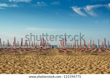 withdrawn yellow umbrellas and sunlongers on the sandy beach in Italy Royalty-Free Stock Photo #121596775