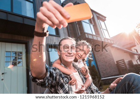 Making photo. Happy handsome father and cute daughter walking outside their house and making photo
