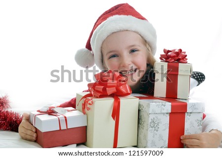 little girl in red santa cap with christmas presents