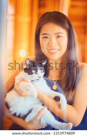 Vintage Photography style of Pretty Asian woman indoor portrait with cat in warm light room background, selected focus.