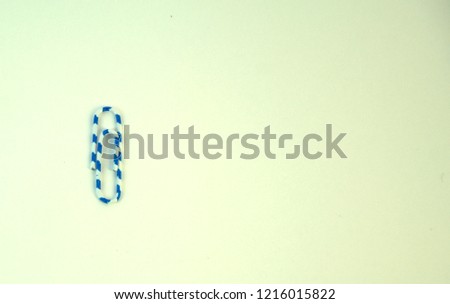 Paper clip in blue and white color on a white background close-up. Isolate
