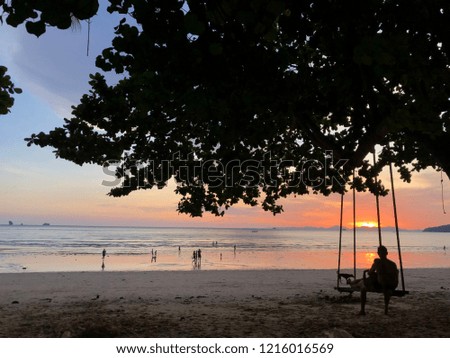 Couple sitting swing with sunset at beach