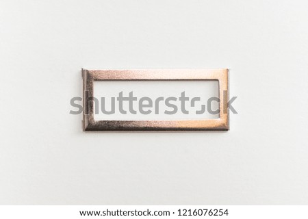Simple metallic frame on white cardboard background.