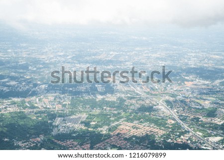 Aerial view from airplane window.  Highway road, urban town, tree and hometown village roof landscape. Big white clouds and shadow in sunny day. North of Bangkok, Thailand. Travel concept.