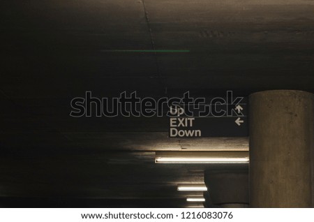 A view of the signs and lights i the parking garage under the ground. 