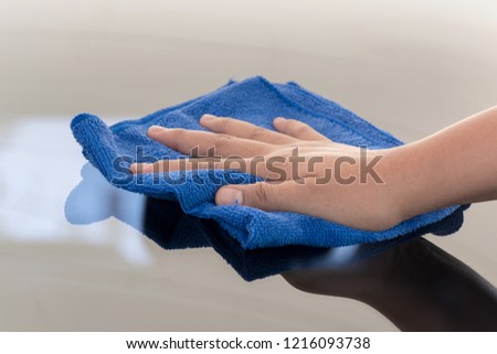 Hand holding a fiber cloth and wiping the car glass.