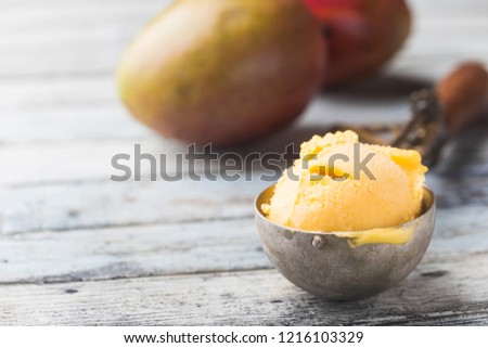 Homemade mango ice cream in a bowls with fresh fruits over white wooden background.