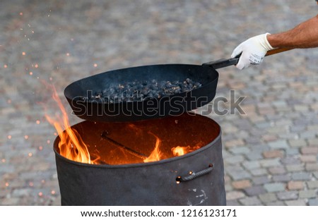 Man roasting chestnuts over a fire in a traditional way