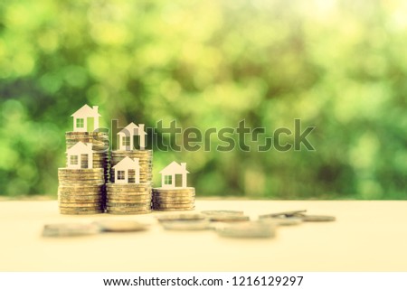 Saving for a first house deposit or a first time home buyer program concept : House models on stacks of coins, depicts saving for a down payment on a real estate or tangible / non depreciation assets Royalty-Free Stock Photo #1216129297