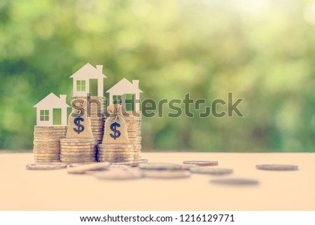Home loan / reverse mortgage and saving for a real estate concept : House model, US dollar money bag on coins, depicts saving for a house or flat manageable and turn a home buying dream into reality