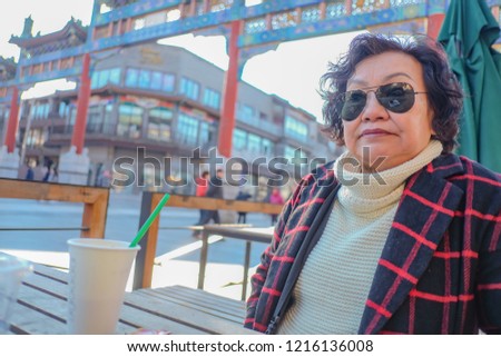 Portrait photo of Asian senior women drinking Coffe on Qianmen street The famous street in beijing Capital City of china
