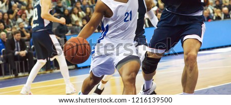 The basketball ball is on the basketball player's hand