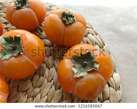 Persimmon ripe fruits on straw plate. High resolution photography.