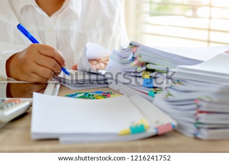 Teacher is checking student homework assignment and report on desk in school for score. Unfinished paperwork stacked in archive with color papers and paper clips. Education and business concept. Royalty-Free Stock Photo #1216241752