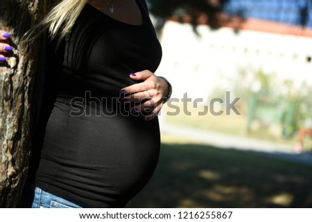 Close-up picture of young pregnant woman hugging her belly