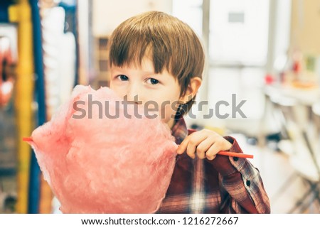The boy eats cotton candy. A child holds a cotton wool on a stick. holiday treat.
