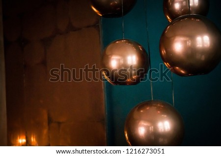 Soft focus sphere bronze lamps with turquoise backdrop. Beautiful reflections. Modern interior in blue and brown colors. Christmas and New Year decoration concept. Empty space for your test and design
