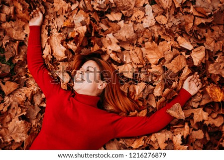 Young woman lying on the autumn leaves in the park