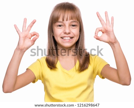 Close-up emotional portrait of caucasian little girl. Funny kid making ok gesture, isolated on white background. Beautiful child laughing looking very happy.