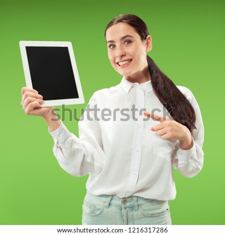 Portrait of a confident casual girl showing blank screen of laptop isolated over green background.
