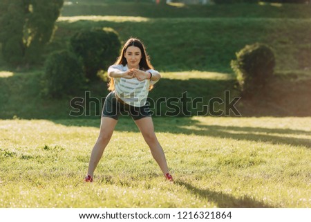 cozy fitness girl making morning stretching exercises outside on sunshine an grass
