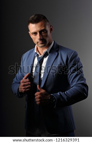 Brutal serious business man thinking in white style blue suit on grey dark shadow background. Closeup portrait