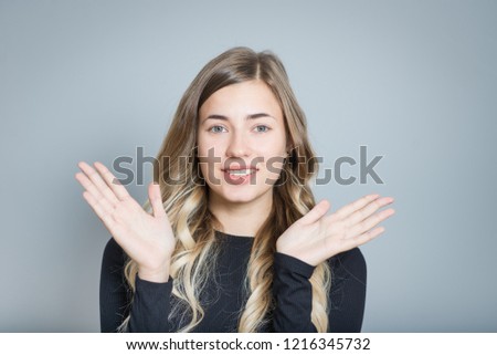 beautiful blonde woman throws up his hands in bewilderment, isolated over black background