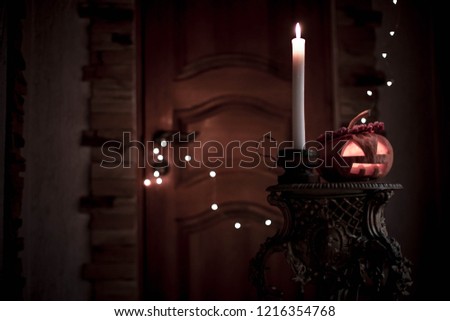 pumpkin for Halloween with a candle and a wreath of berries on his head. pumpkin on a dark background of the castle doors