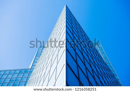 The straight line is moving from bottom up of a modern facade of an office tower building in Tel Aviv city. The blue clear sky is reflected on the glass surface of the tower.