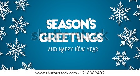 Season's Greetings and Happy New Year greeting card concept with white snowflakes and blue background Royalty-Free Stock Photo #1216369402