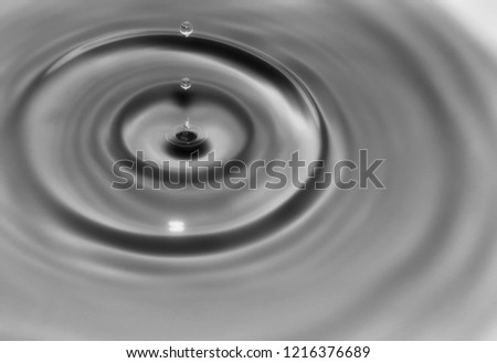 Macro closeup of water droplet using high speed technique. The droplet is frozen in time and concentric circles are rippling away. Black and white conversion.