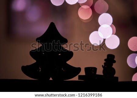 Silhouette of Christmas tree and snowman and in the background christmas lights bokeh 