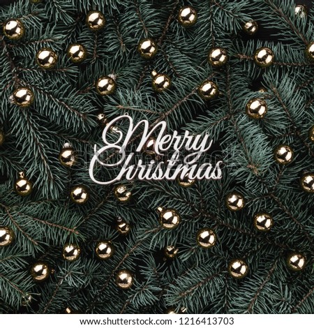 Winter background of fir branches. Adorned with golden baubles and Merry Christmas inscription. Xmas card. Top view. Xmas congratulations. Square card. Royalty-Free Stock Photo #1216413703