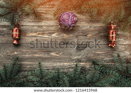 Old wood background with fir branches with toys. Space for a greeting message. Christmas card. Top view. Light effect.