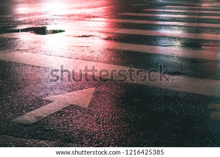 The red traffic light on a crosswalk at night on wet asphalt