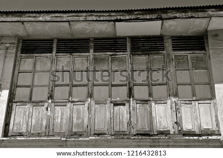 Rustic wooden louvred shuttered windows, showing signs of decay and rot. 