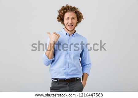 Portrait of a cheerful young man with curly hair isolated over white background, pointing finger away