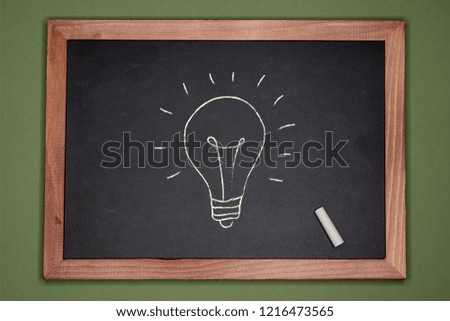 Idea concept. Lamp on chalkboard on green background
