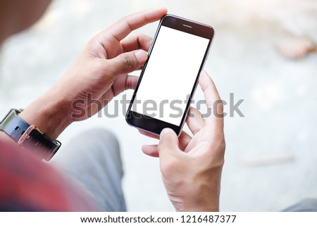 Cropped shot view of man hands holding smart phone with blank copy space screen for your text message or information content, female reading text message on cell telephone during in urban setting. Royalty-Free Stock Photo #1216487377