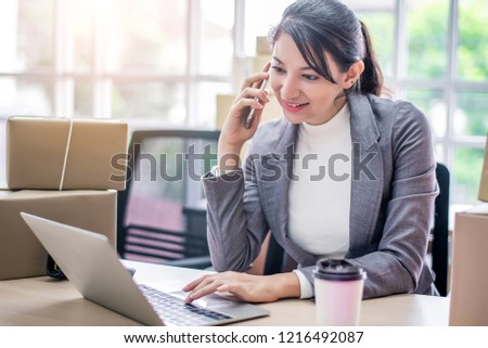 Happy young Asian woman answer phone from customer with her business online shopping at office.