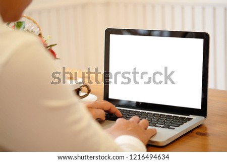 A Man using mockup laptop computer on wood table.