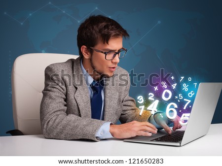 Handsome young man sitting at desk and typing on laptop with 3d numbers comming out