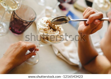 Woman's hands tasting and enjoying a cold dessert in a glass.