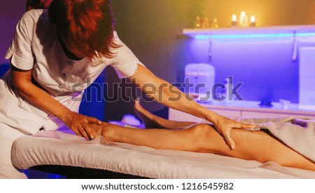 Young woman having feet massage in beauty salon, close up view
